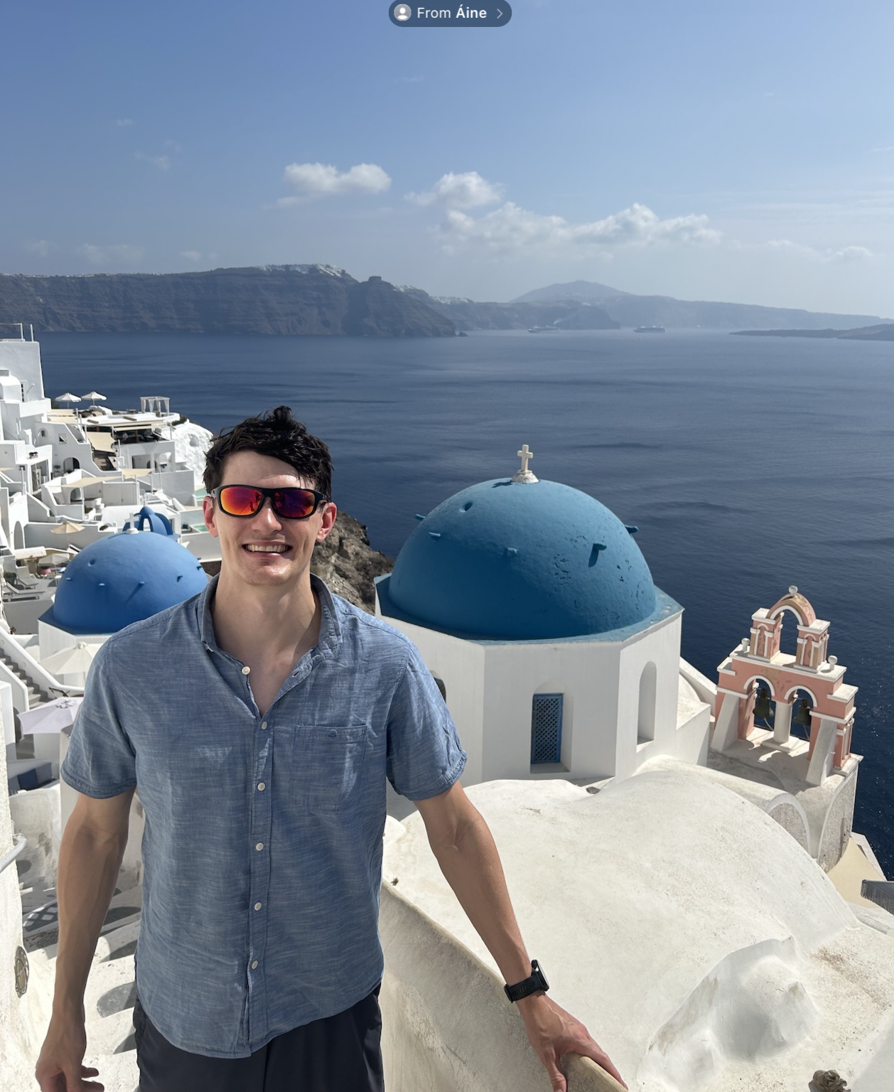 Rowan Swiers overlooking the sea and blue-domed buildings in Santorini